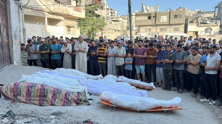 Palestinians pray next to the bodies of Palestinians killed in an Israeli strike on a school sheltering displaced people, amid the Israel-Hamas conflict, in Gaza City, August 10, 2024. REUTERS/Abed Sabah