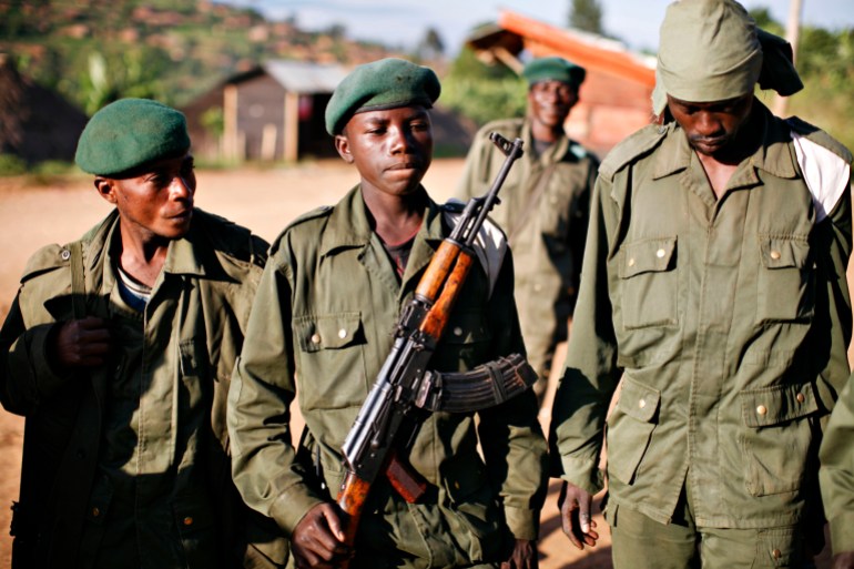 A child soldier (C), known as "Kadogo," meaning "small one" in Swahili, stands at the front line at Kanyabayonga in eastern Congo, November 17, 2008. Snatched from their homes by armed men who force them to carry ammunition, fight and kill, beaten if they refuse, east Congo's child soldiers are teenage victims of an unforgiving war. Child protection agencies report a surge in recruitment of under-18 soldiers by warring factions in Democratic Republic of Congo's eastern North Kivu province, where increased fighting since August has displaced hundreds of thousands of people. Picture taken November 17, 2008. REUTERS/Finbarr O'Reilly (DEMOCRATIC REPUBLIC OF CONGO)