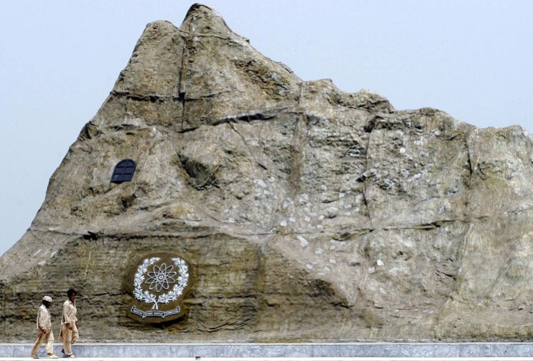 Two Pakistani labourers walk past the replica of the Chagi mountain, where Pakistan held its first ever nuclear test, in Islamabad, 01 July 2004. President Pervez Musharraf said Pakistan will conduct an "important" missile test in two months time, stressing that its nuclear and missile programmes remain irreversible. AFP PHOTO/Farooq NAEEM (Photo by FAROOQ NAEEM / AFP)