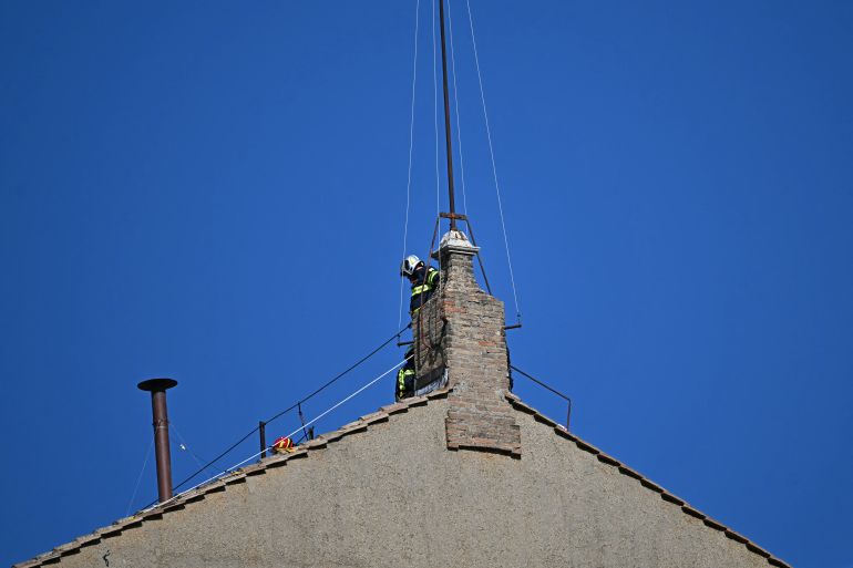 This photograph shows a view of the chimney (L) on the roof of the Sistine Chapel as it is being installed in The Vatican, on May 2, 2025.
