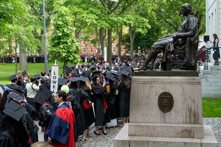 (FILES) Graduating students stand next to a statue of John Harvard at the 374th Harvard Commencement in Harvard Yard in Cambridge, Massachusetts, on May 29, 2025.