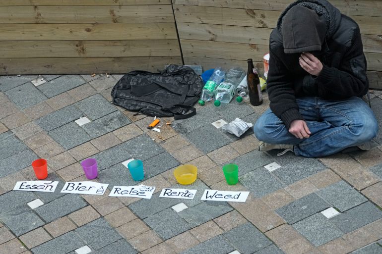 A young man begs for money for food, beer, travel, pension and weed in a pedestrian street in Dortmund, Germany, while Europe's biggest economy is still shrinking for a second consecutive year, Thursday, Oct. 24, 2024. (AP Photo/Martin Meissner)