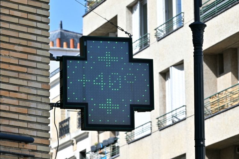 This photograph shows a pharmacy sign indicating a temperature of 40 degrees Celsius in central Paris on August 12, 2025.