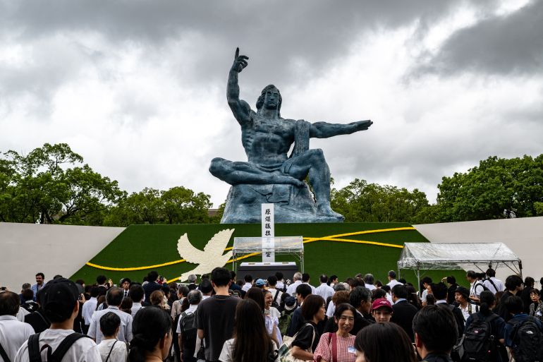 People stand in front of the Peace statue after the annual memorial ceremony for the victims at the Peace Park in Nagasaki on August 9, 2025, to mark the 80th anniversary of the atomic bombing during WWII. (Photo by Philip FONG / AFP)